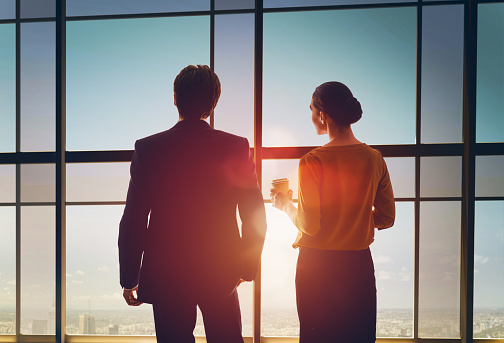 team of successful business people. two businessmen resting and talking in the office. man and woman look at the city from the window of the business center.