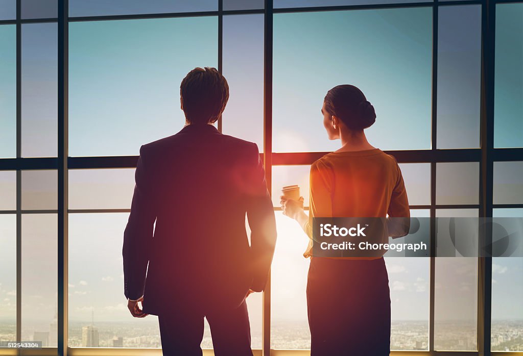 man and woman look at the city team of successful business people. two businessmen resting and talking in the office. man and woman look at the city from the window of the business center. Looking Through Window Stock Photo