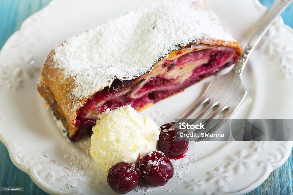 Plate with cherry strudel closeup. Plate with cherry strudel and fork on blue table. Baked Stock Photo