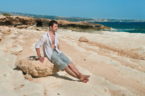 man sitting on rock at sea near Coral Bay, cyprus