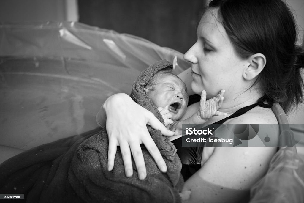 Mother Embracing Her Newborn after Home Water Birth Black and white image of a young mother holding her newborn son after giving birth at home. Water Birth Stock Photo