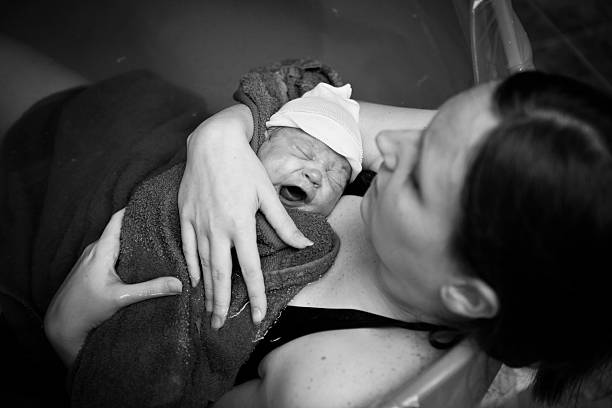 Mother Embracing Her Newborn after Home Water Birth Black and white image of a young mother holding her newborn son after giving birth at home. water birth photos stock pictures, royalty-free photos & images
