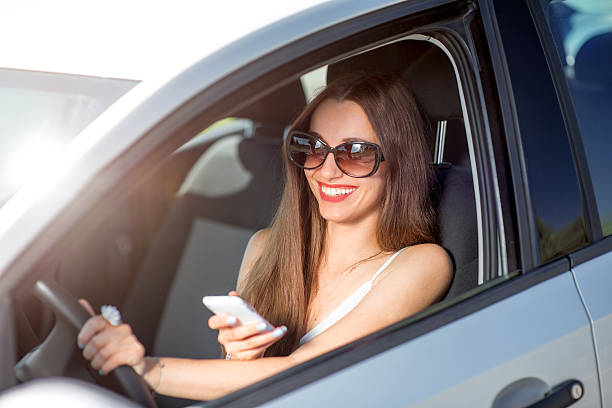 istock Young smiling woman using phone while driving her car 512550665
