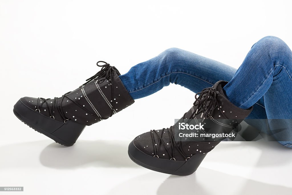 Girl lying in the moon boots. Girl lying in the moon boots and jeans on a white background. Funny winter boots. Arts Culture and Entertainment Stock Photo