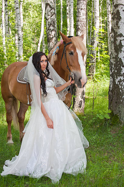femme en robe de fiancée à côté d'un cheval - adult beautiful wedding bride photos et images de collection