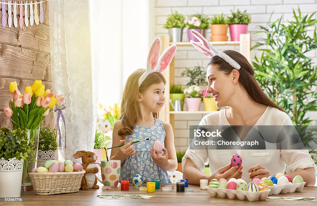 family preparing for Easter Happy easter! A mother and her daughter painting Easter eggs. Happy family preparing for Easter. Cute little child girl wearing bunny ears on Easter day. Basket Stock Photo