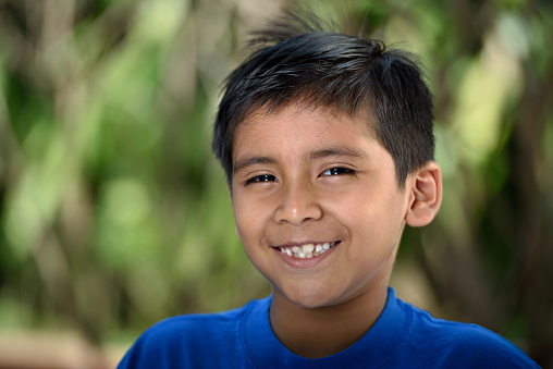 Headshot of latino boy with smile in nature