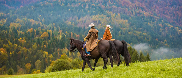 vaqueiro ou vaqueira andando em um prado - horseback riding cowboy riding recreational pursuit - fotografias e filmes do acervo