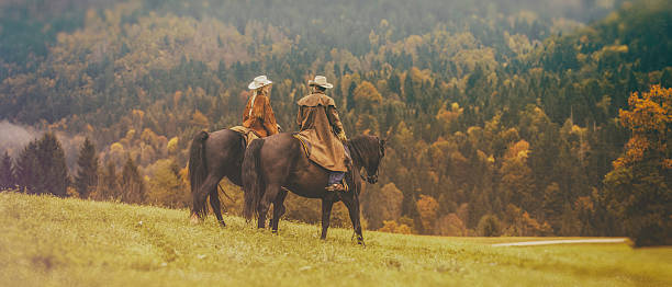 ковбой и скотнице на лошадях через луг - wide meadow two animals horse стоковые фото и изображения