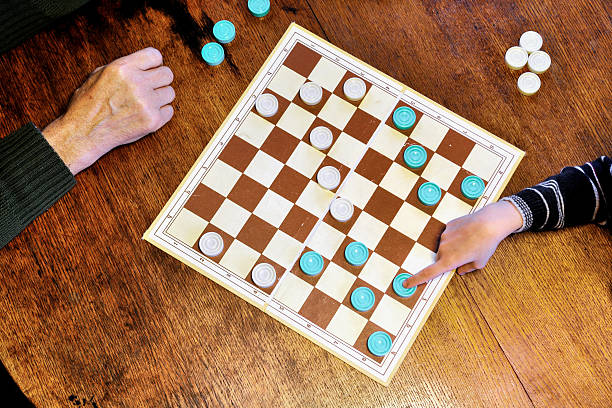 Grandfather and grandson are playing checkers stock photo