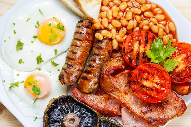 inglese completa colazione con pancetta, salsiccia, uova, stufati in salsa di pomodoro e funghi - morning tomato lettuce vegetable foto e immagini stock