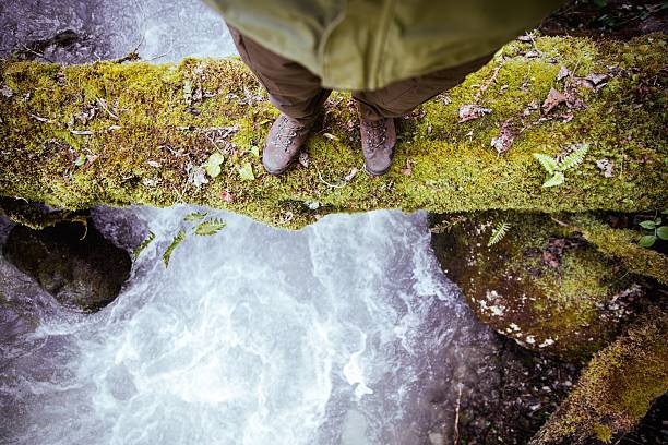 istock Feet Man standing on log over river outdoor 512573396