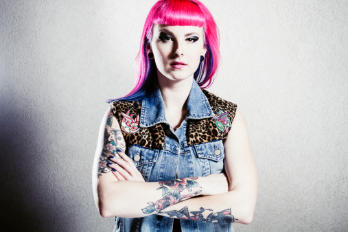 Portrait series of rockabilly girl with pink and blue hair against white wall.