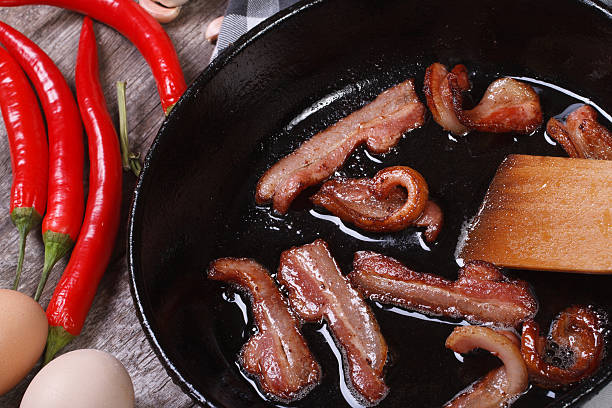 istock fried bacon in a pan and chili, horizontal. macro 512576147