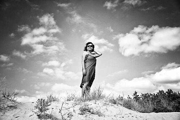 Mature hispanic woman in swimsuit and wrap standing in sand dunes