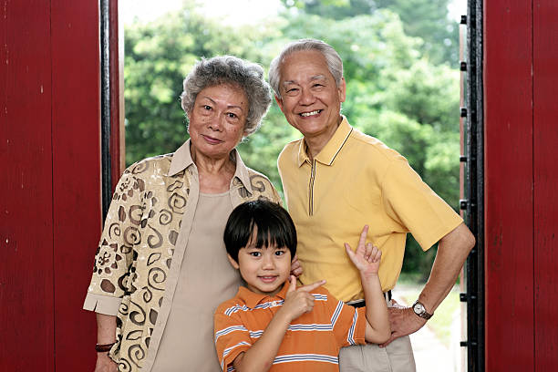 Asian grandmother and grandson drinking Chinese tea together in yard.