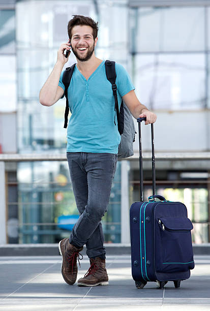 istock Young man smiling with suitcase at airport 512577523