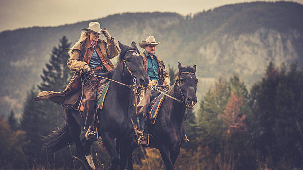 vaqueiro e vaqueira passeio a cavalo através do bosque - horseback riding cowboy riding recreational pursuit - fotografias e filmes do acervo