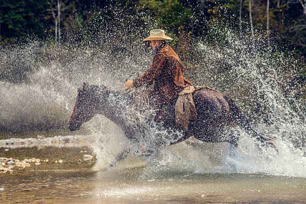 istock Cowboy riding across a river in the forest 512592878