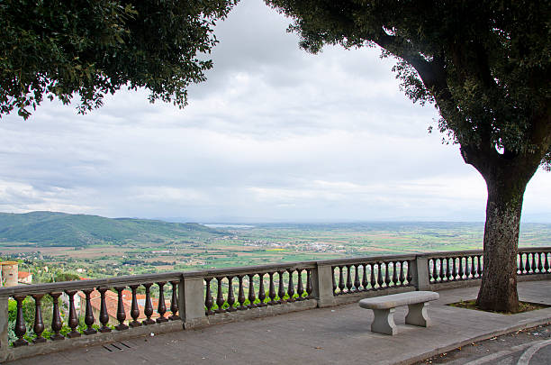 Val d'Chiana From Piazza Garibaldi in Cortona, Italy Rain clouds move into the Val d'Chiana, as seen Piazza Garibaldi in Cortona, with stunning fields of green, yellow and orange awaiting the deluge. stone bench top view stock pictures, royalty-free photos & images