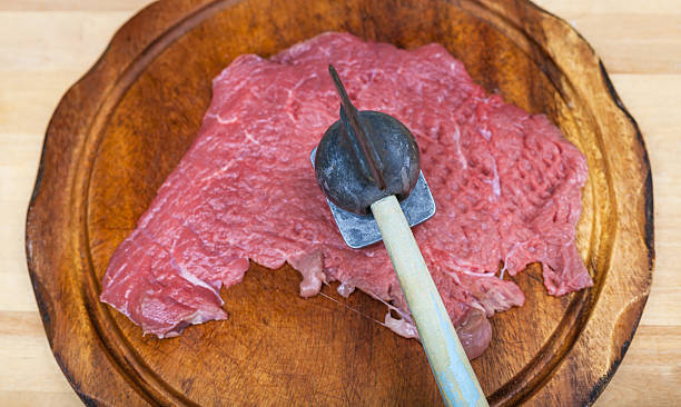 top view of raw veal are beat by meat tenderizer