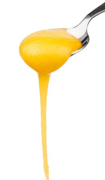 istock yellow honey flowing down from spoon close up 512596570