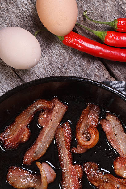 istock fried bacon in pan and chili, eggs on the table 512599803