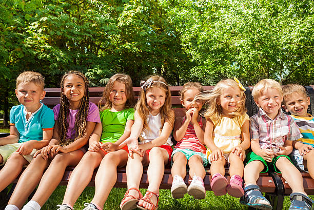 istock Kids in row on the bench, summer park 512600401