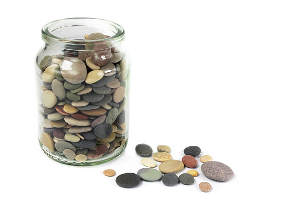 Pebbles or Beach stones in a glass jar on white background