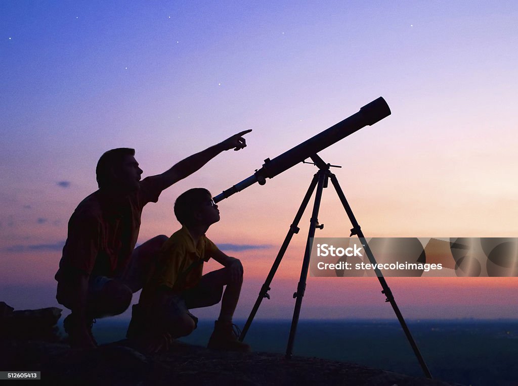 Telescope A young boy looking thru a telescope at sunset with his father. Astronomy Stock Photo