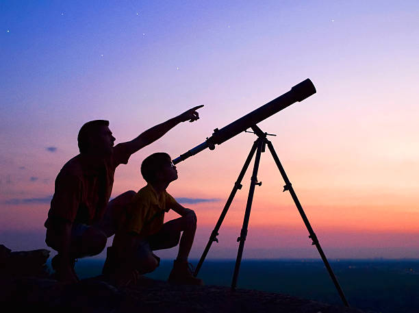 Telescope A young boy looking thru a telescope at sunset with his father. telescopic equipment stock pictures, royalty-free photos & images