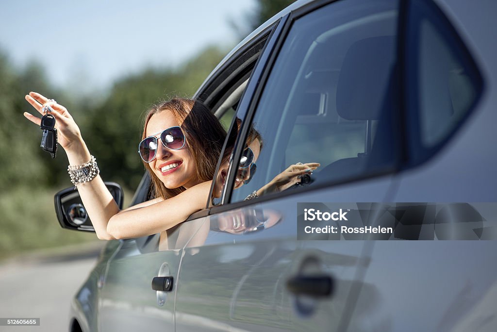 Car driver woman happy showing keys out window Car driver woman happy showing car keys out window Car Key Stock Photo