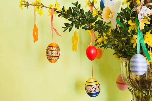 Easter eggs and other decoration hanging on forsythia branches
