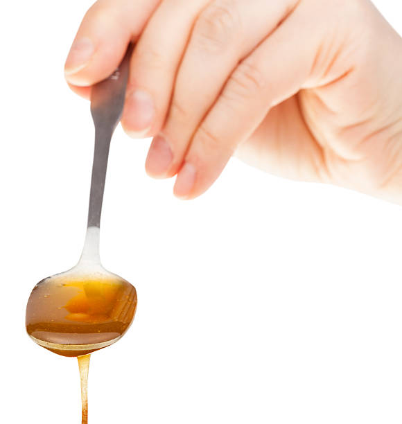 istock front view of hand holds metal spoon with honey 512618232