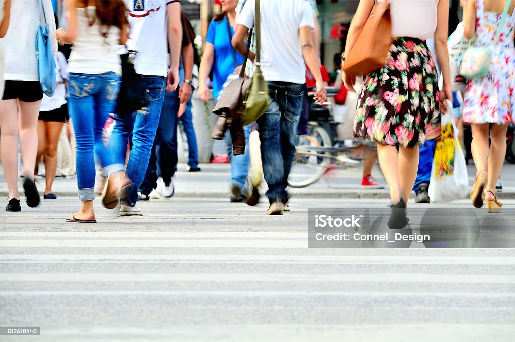 Motion blurred pedestrians crossing sunlit street People Stock Photo