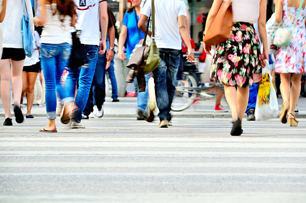 Motion blurred pedestrians crossing sunlit street Motion blurred pedestrians crossing sunlit street crossing sign stock pictures, royalty-free photos & images