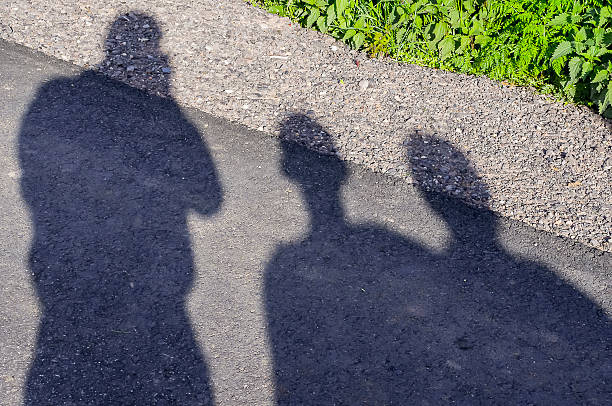 istock Three shadows of people on the pavement 512618742