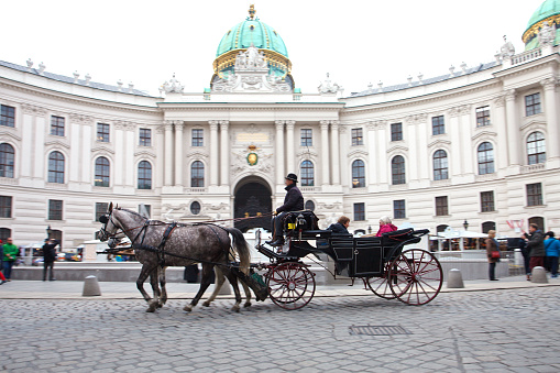 Vienna, Austria - December 3, 2015: Tourists took an afternoon horse carriage ride along the Hofburg Palace in Vienna. Panning photo.