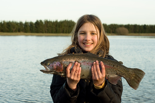 Portrait of young happy girl holding the trout