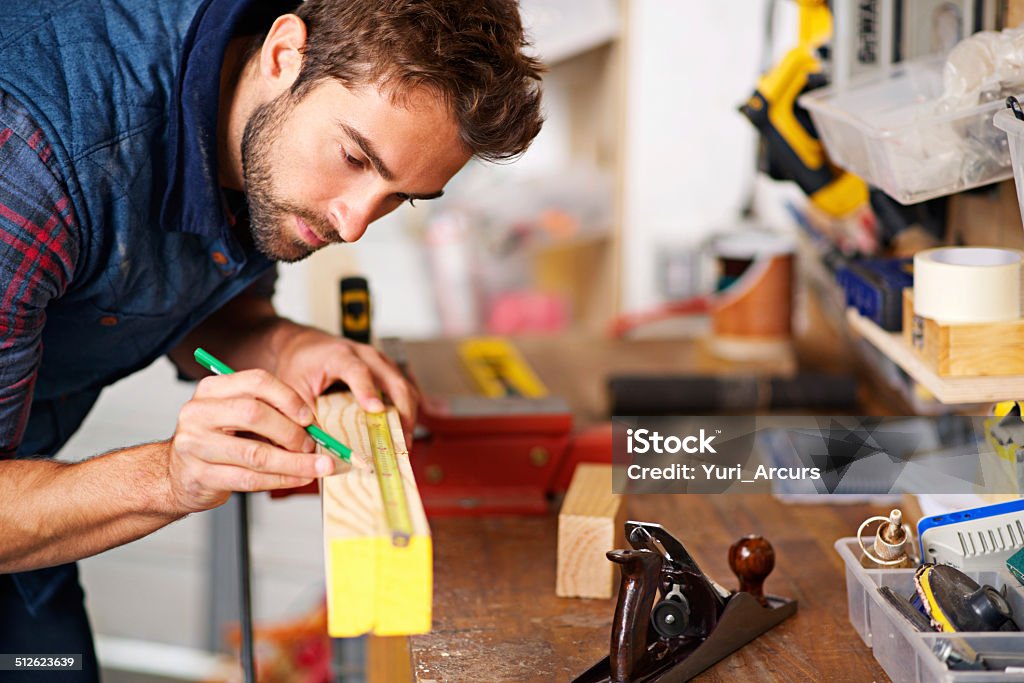 Working that wood Shot of a handsome young carpenter measuring a piece of wood 30-34 Years Stock Photo