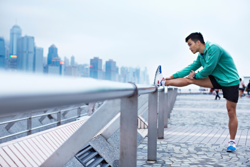 Shot of a young asian man warming up for a jog along the Hong Kong skyline