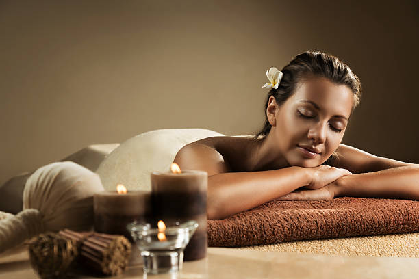 The girl relaxes in the spa salon The girl relaxes in the spa salon. Beautiful setup with candles and herbal balls on the foreground. spas and spa treatments stock pictures, royalty-free photos & images