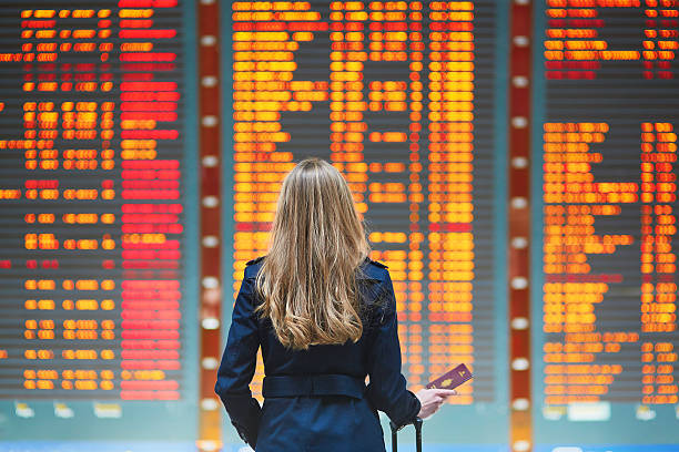 jeune femme à l'aéroport international de - tableau des départs et arrivées photos et images de collection