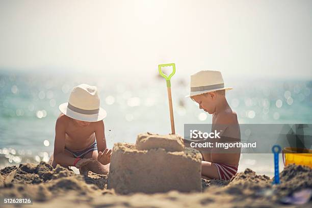 Two Brothers Building A Sandcastle On Beautiful Beach Stock Photo - Download Image Now