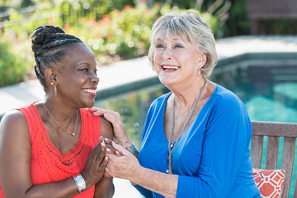istock Mature multi-racial women sitting by swimming pool 512628384