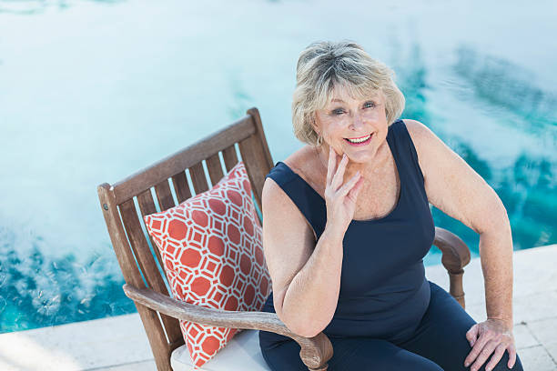 istock Senior woman smiling, sitting by swimming pool 512628452