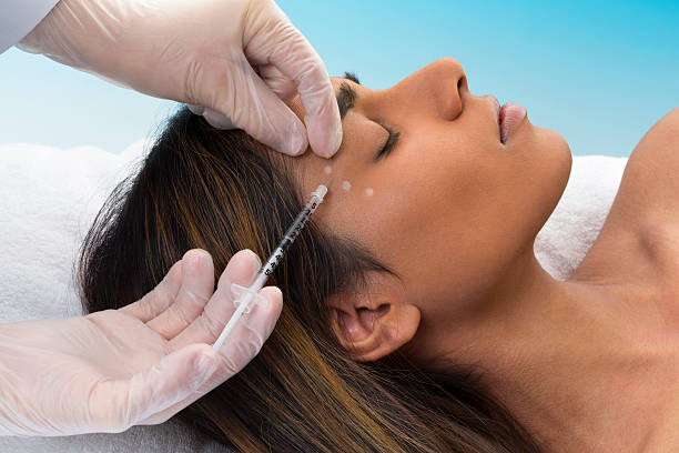 Mixed Race Woman Receiving Botox Injection Young mixed race woman lying down receiving botox injection. botulinum toxin injection stock pictures, royalty-free photos & images