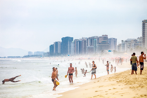 Barra da Tijuca, Brazil - February 9, 2013: Public beach full of local people relaxing, playing ball, jogging and swimming.