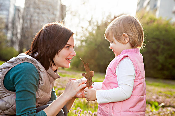 istock Mother and daughter looking on leaf in park 512630316