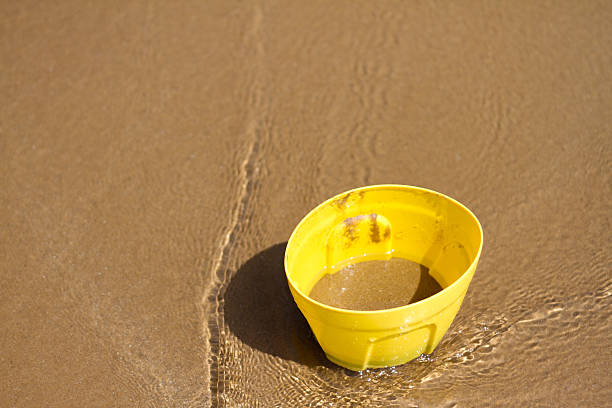 istock Yellow Pail on Sunlit Beach with Tide Going Out 512640688